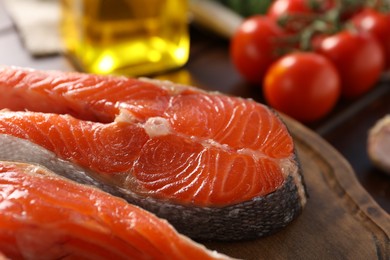 Photo of Board with fresh salmon steaks on table, closeup