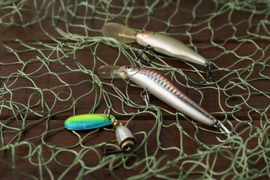 Fishing net and different lures on wooden table