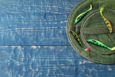 Fishing net and lures on blue wooden background, flat lay. Space for text