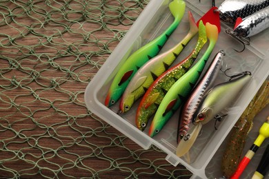 Fishing baits, float and net on wooden table, top view