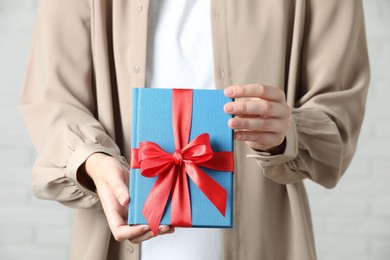 Photo of Woman holding book tied with red ribbon indoors, closeup