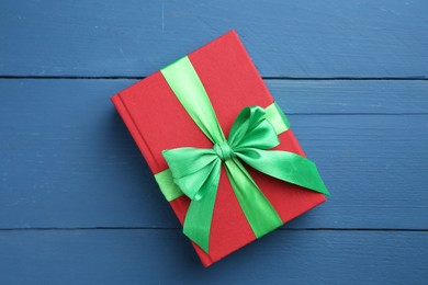 Photo of Books tied with green ribbon as gift on blue wooden table, top view