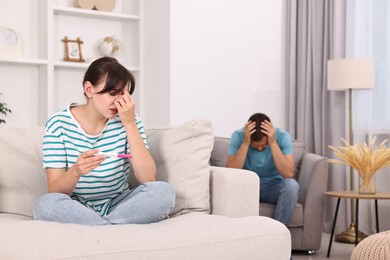 Photo of Worried young couple with pregnancy test at home