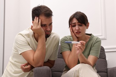Photo of Worried young couple with pregnancy test at home