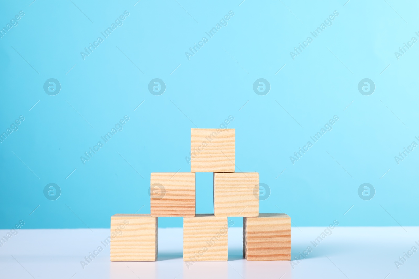 Photo of Many wooden cubes on white table against light blue background