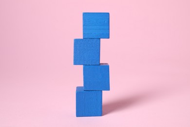 Photo of Stack of blank blue cubes on pink background