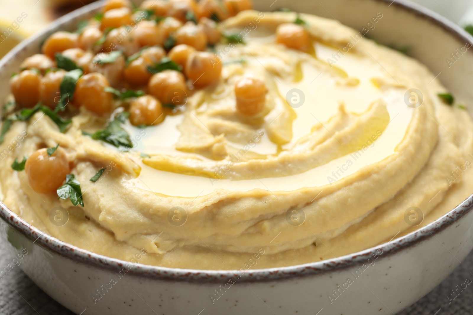 Photo of Delicious hummus with olive oil, chickpeas and parsley in bowl, closeup