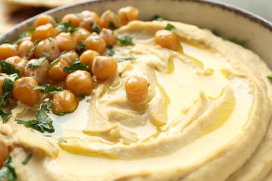 Photo of Delicious hummus with olive oil, chickpeas and parsley in bowl, closeup