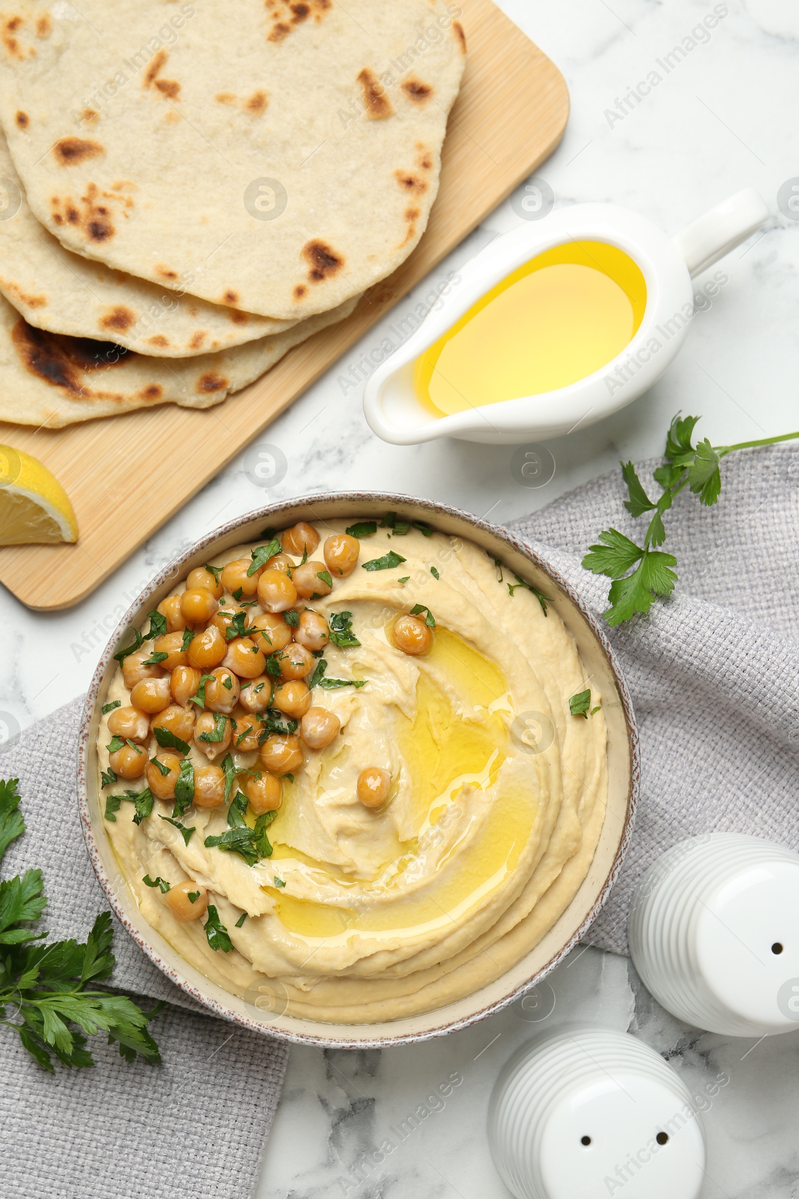 Photo of Delicious hummus with olive oil and chickpeas served on white table, flat lay