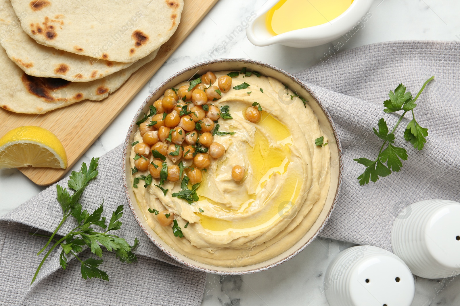 Photo of Delicious hummus with olive oil and chickpeas served on white table, flat lay