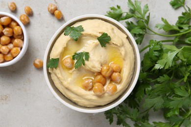 Photo of Delicious hummus with olive oil, chickpeas and parsley on light grey table, flat lay