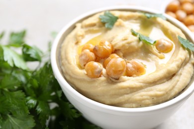 Photo of Delicious hummus with olive oil and chickpeas on light table, closeup