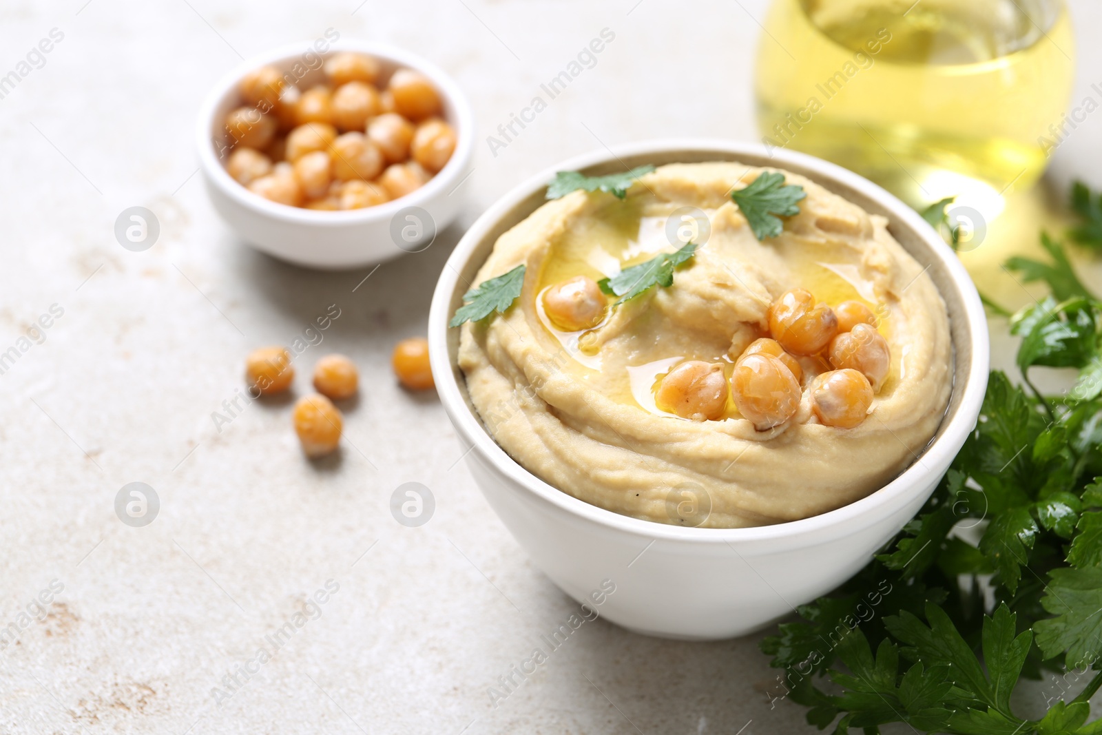 Photo of Delicious hummus with olive oil and chickpeas on light table