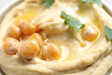 Photo of Delicious hummus with olive oil, chickpeas and parsley in bowl, closeup