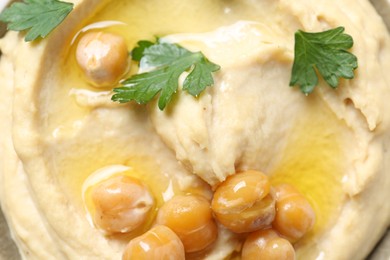 Photo of Delicious hummus with olive oil, chickpeas and parsley in bowl, top view