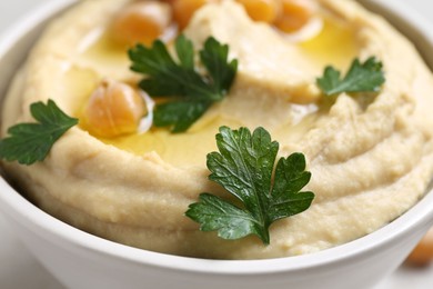 Photo of Delicious hummus with olive oil, chickpeas and parsley in bowl on table, closeup