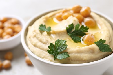 Delicious hummus with olive oil, chickpeas and parsley in bowl on table, closeup