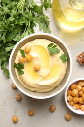 Photo of Delicious hummus with olive oil, chickpeas and parsley on light textured table, flat lay