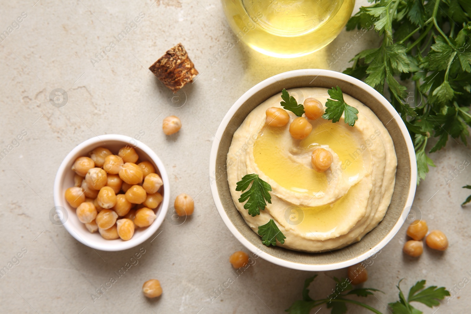 Photo of Delicious hummus with olive oil, chickpeas and parsley on light textured table, flat lay