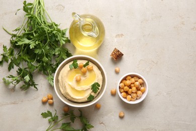 Photo of Delicious hummus with olive oil, chickpeas and parsley on light textured table, flat lay