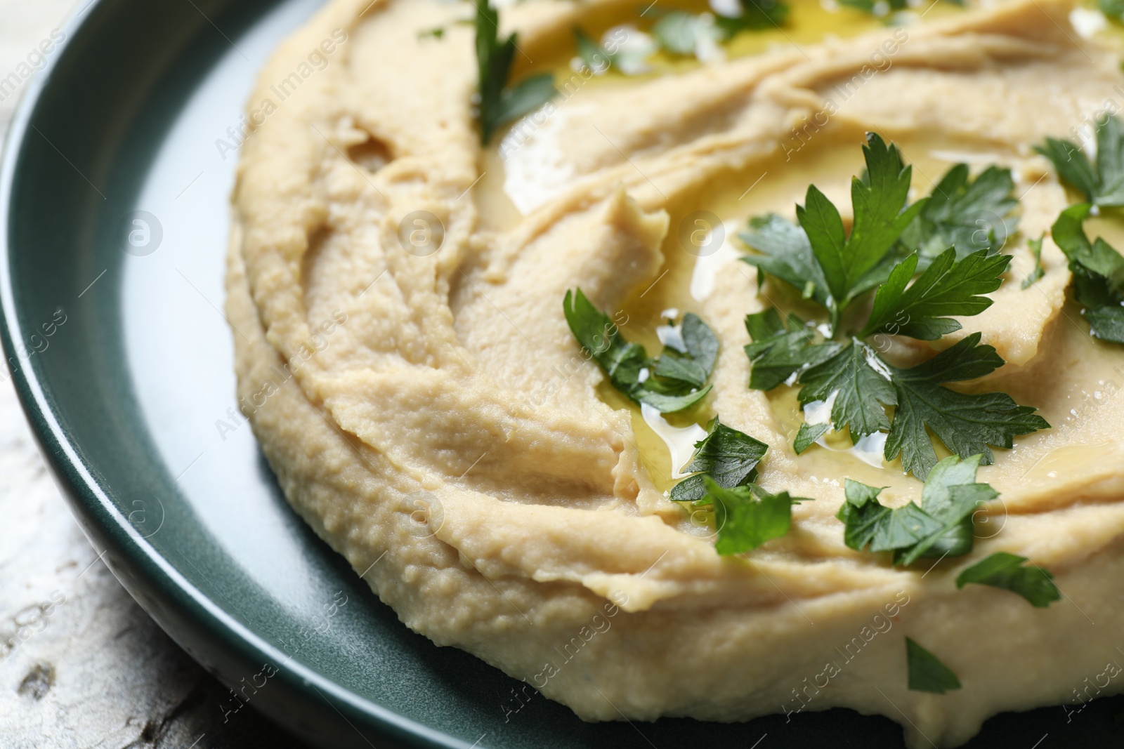 Photo of Delicious hummus with olive oil and parsley on table, closeup