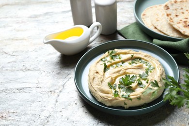 Photo of Delicious hummus with olive oil and parsley on grey textured table, space for text