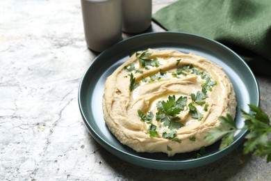 Delicious hummus with olive oil and parsley on grey textured table