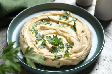 Photo of Delicious hummus with olive oil and parsley on grey table, closeup