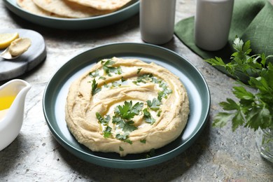 Delicious hummus with olive oil and parsley on grey textured table