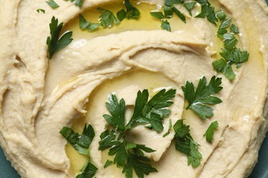 Photo of Delicious hummus with olive oil and parsley on plate, top view