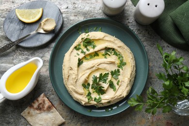 Delicious hummus with olive oil served on grey textured table, flat lay