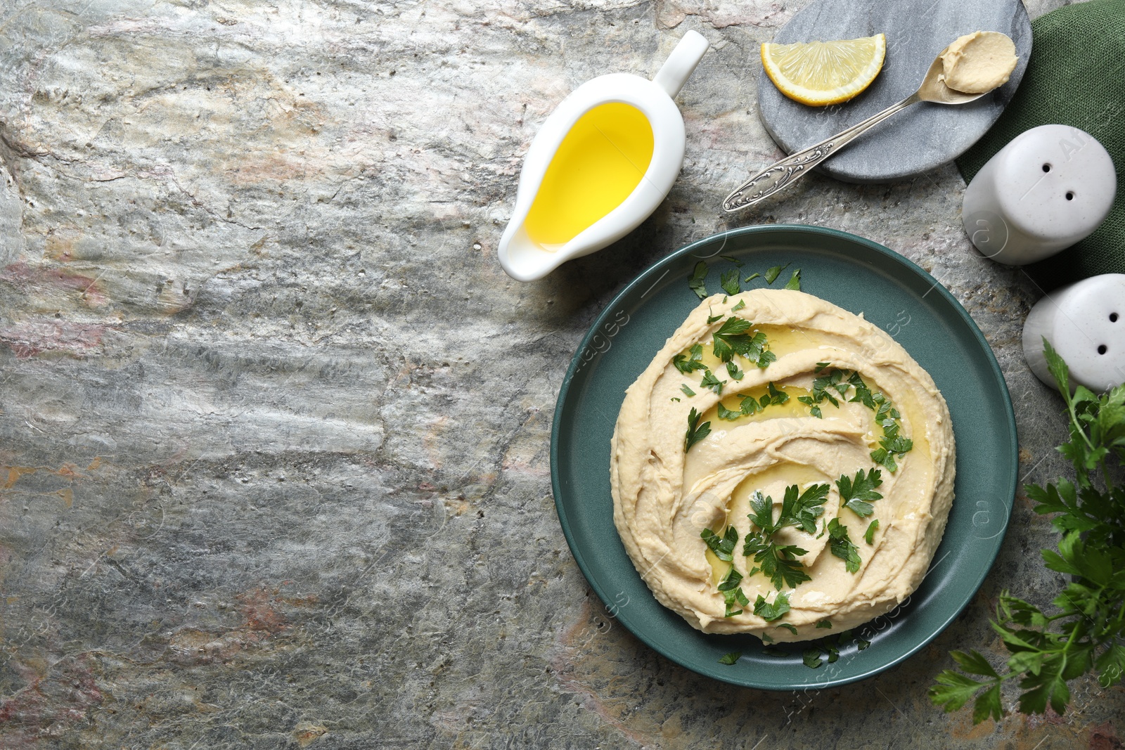 Photo of Delicious hummus with olive oil served on grey textured table, flat lay. Space for text