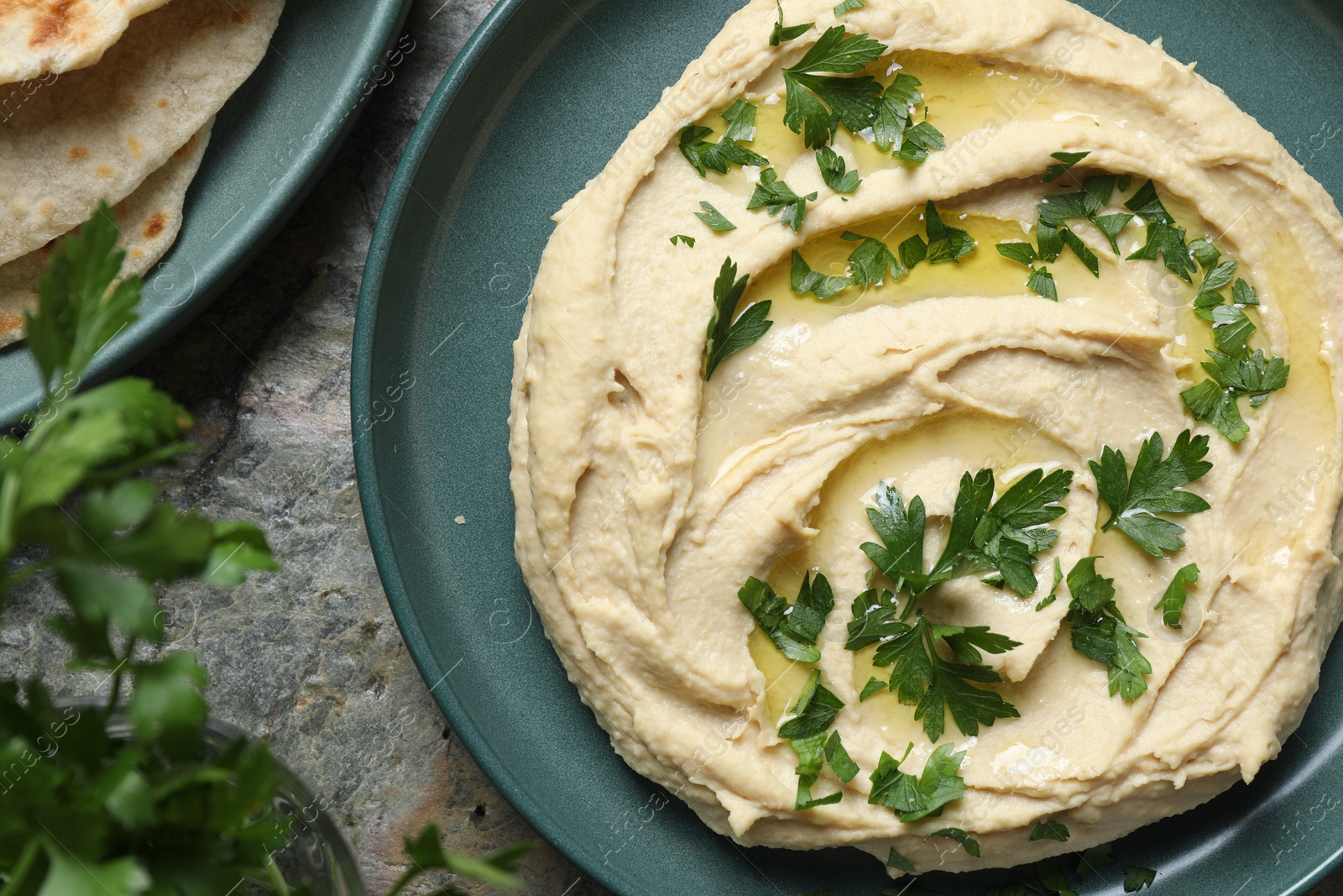 Photo of Delicious hummus with olive oil and parsley on grey table, flat lay