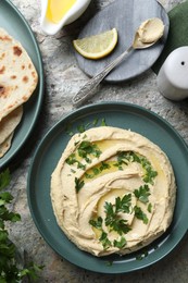 Photo of Delicious hummus with olive oil served on grey textured table, flat lay