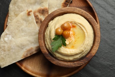 Photo of Delicious hummus with olive oil, chickpeas in bowl and pita on grey table, flat lay