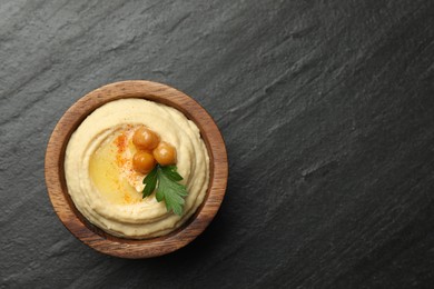 Photo of Delicious hummus with olive oil, chickpeas and parsley in bowl on grey textured table, top view. Space for text