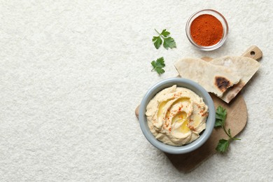 Photo of Delicious hummus with olive oil and paprika served on white textured table, flat lay. Space for text