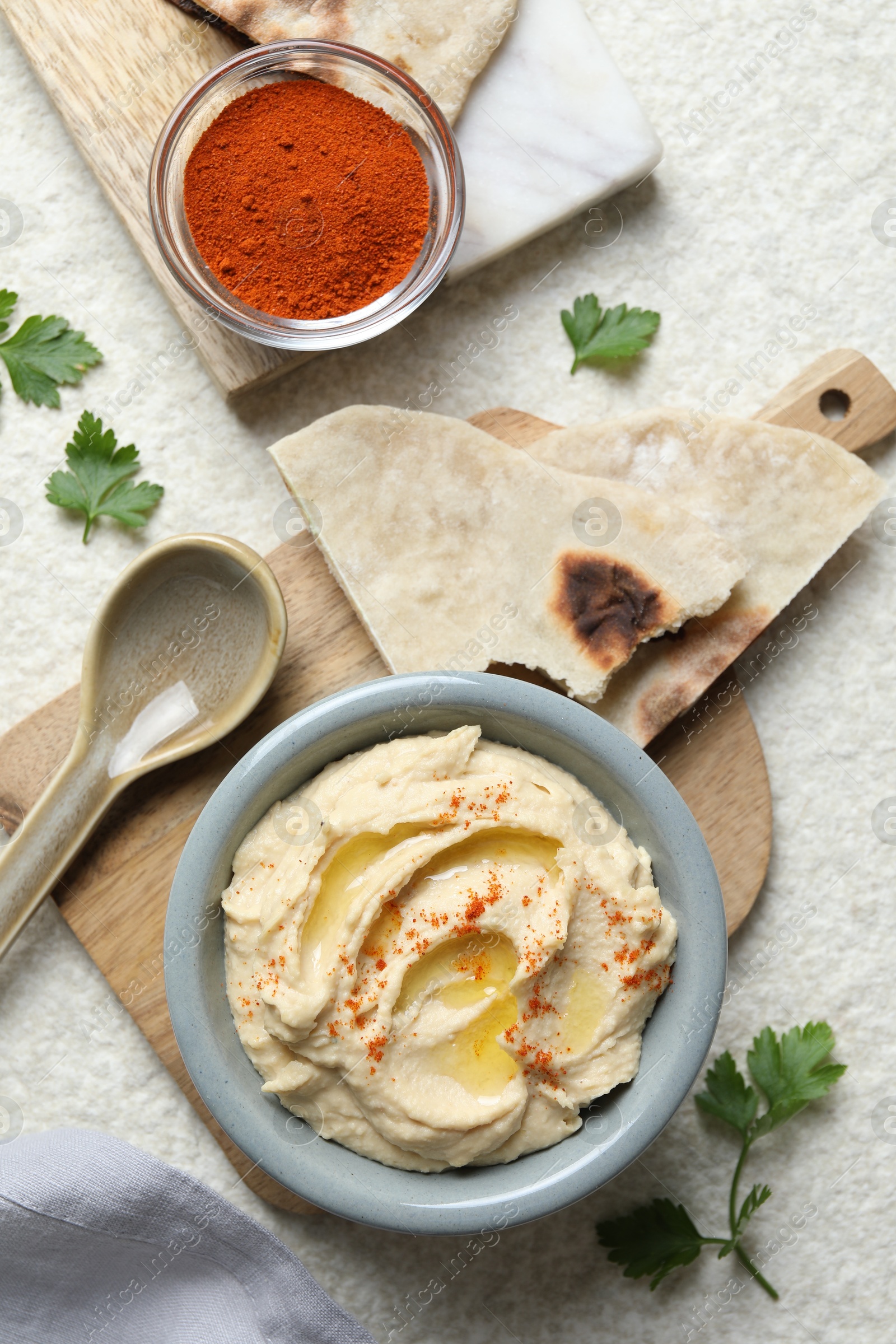 Photo of Delicious hummus with olive oil and paprika served on white textured table, flat lay