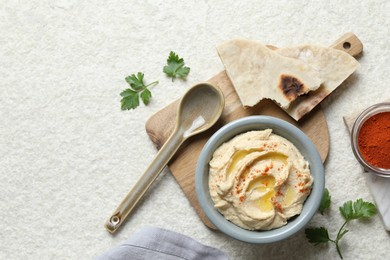 Photo of Delicious hummus with olive oil and paprika served on white textured table, flat lay