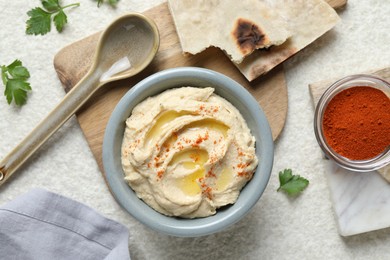 Photo of Delicious hummus with olive oil and paprika served on white textured table, flat lay