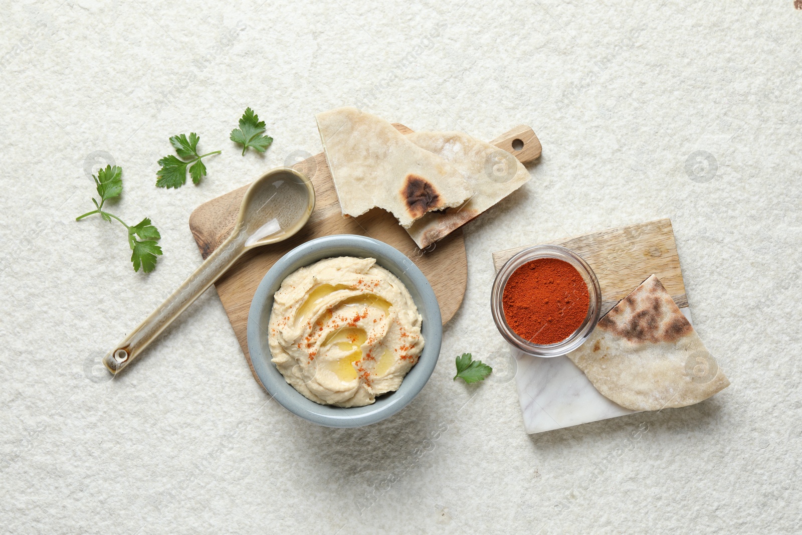 Photo of Delicious hummus with olive oil and paprika served on white textured table, flat lay