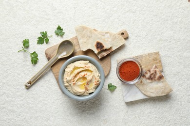 Photo of Delicious hummus with olive oil and paprika served on white textured table, flat lay