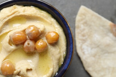 Photo of Delicious hummus with olive oil and chickpeas in bowl on grey table, top view. Space for text