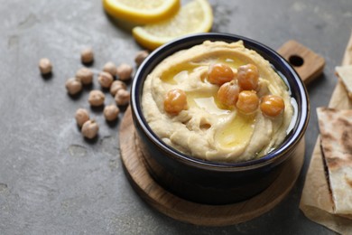 Photo of Delicious hummus with olive oil and chickpeas in bowl on grey table