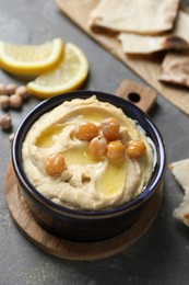 Delicious hummus with olive oil and chickpeas in bowl on grey table