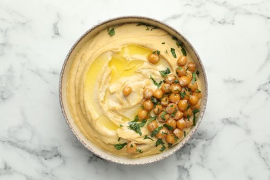 Photo of Delicious hummus with olive oil, chickpeas and parsley in bowl on white marble table, top view