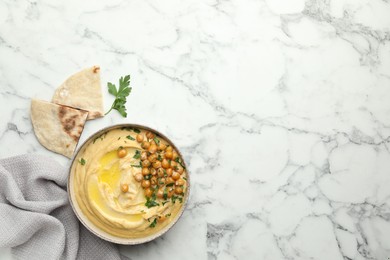 Delicious hummus with olive oil, chickpeas and pita on white marble table, flat lay. Space for text