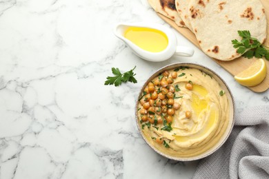 Photo of Delicious hummus with olive oil, chickpeas and pita on white marble table, flat lay. Space for text