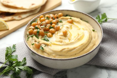 Photo of Delicious hummus with olive oil, chickpeas and parsley in bowl on table