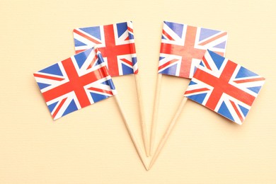 Small paper flags of United Kingdom on beige background, top view